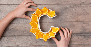 Frutas com vitamina C Duas mãos ajustando a posição de dez laranjas num formato de C.