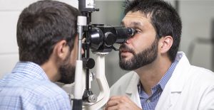 Médico oftálmico visualizando os olhos de seu paciente através de um aparelho.