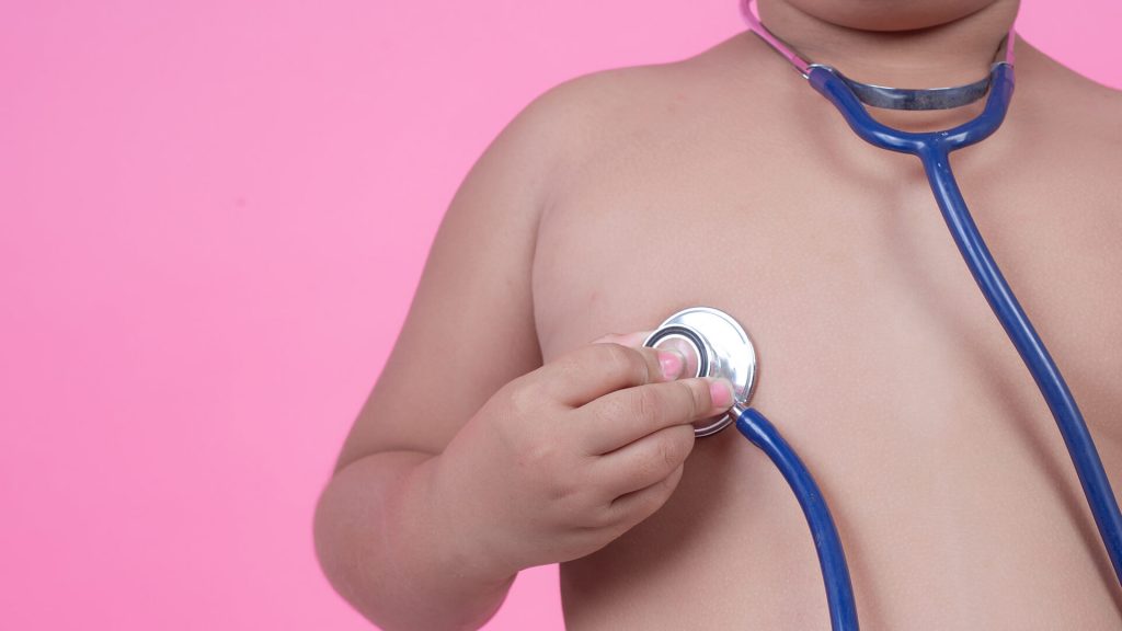 Sedentarismo Infantil Criança sem camisa e segurando um estetoscópio na altura do peito