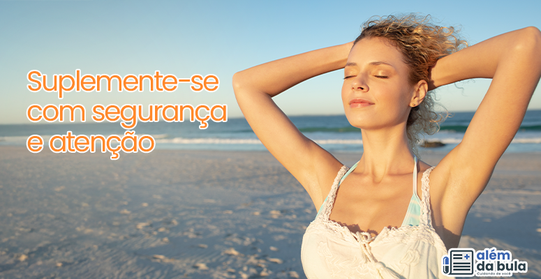 Na imagem consta uma mulher na praia, ela está tomando sol e com as mãos nos cabelos, enquanto sorri. Na imagem tem a seguinte frase ilustrativa: 'Como suplementar com segurança'.