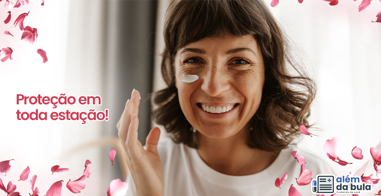 Na imagem tem uma mulher sorrindo, ela tem franja e cabelo curto. Ela tem creme no rosto e está com a mão levantada como se estivesse passando no rosto. Na imagem também tem flores ilustrativas e a seguinte frase: 'Proteção em toda estação'.
